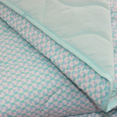 Manta acolchoada azul claro com padrão geométrico e forro azul claro dobrada