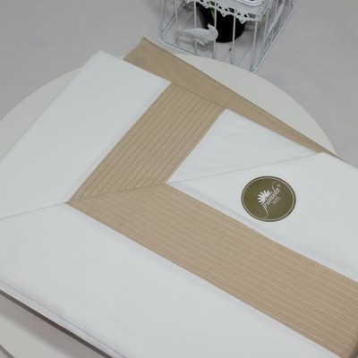 Lençol branco e bege dobrado com padrão riscado sobre superfície clara