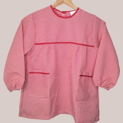 Blusa infantil xadrez vermelho e branco com bolsos e mangas compridas pendurada num cabide
