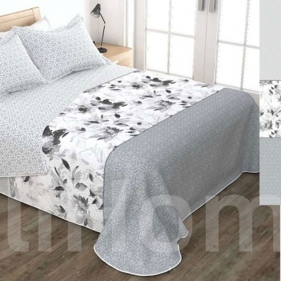 Conjunto de roupa de cama cinza e branco com padrão floral em quarto com piso de madeira.