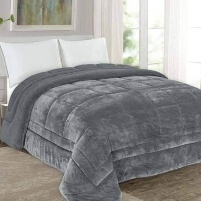 Cama de casal com edredão cinzento de tecido aveludado e almofadas brancas numa sala clara