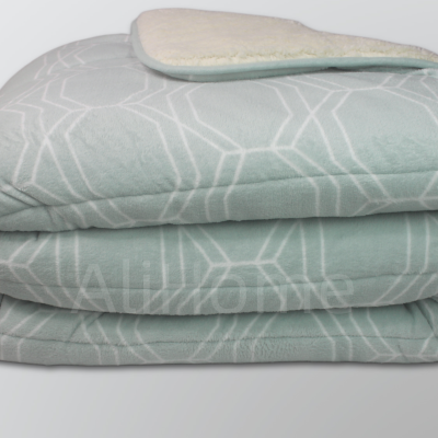 Manta cinza com padrão geométrico branco dobrada mostrando forro branco felpudo