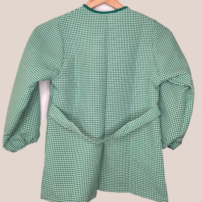 Casaco verde xadrez de mangas compridas com cinto pendurado num cabide de madeira