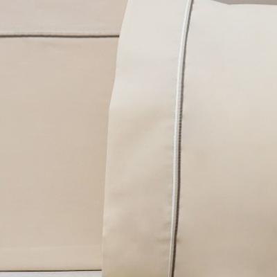 Fronha e lençol plano bege claro com linha cinza na borda sobre fundo de madeira clara