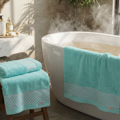 Toalhas de banho turquesa com padrão quadriculado penduradas numa banheira branca e sobre um banco, em casa de banho moderna.