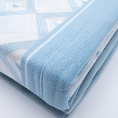 Manta branca e azul claro dobrada com padrão geométrico e textura macia