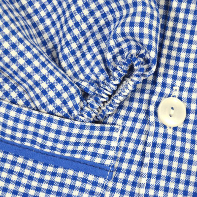 Detalhe de camisa xadrez azul e branco com botão e acabamento em fita azul