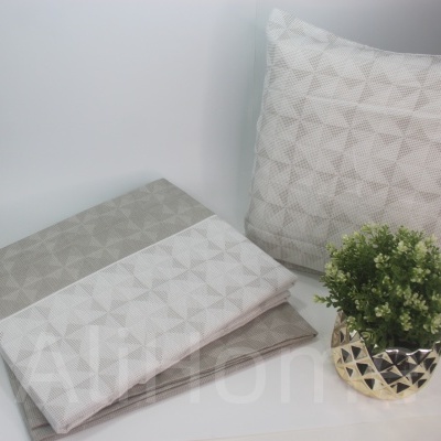 Conjunto de têxteis de cama com padrão geométrico em tons neutros com vaso dourado e planta