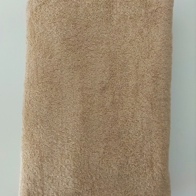 Toalha bege de algodão dobrada sobre fundo branco