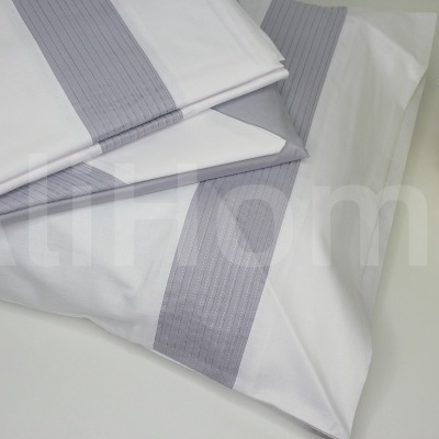 Conjunto de roupa de cama branca com faixa cinzenta e planta decorativa