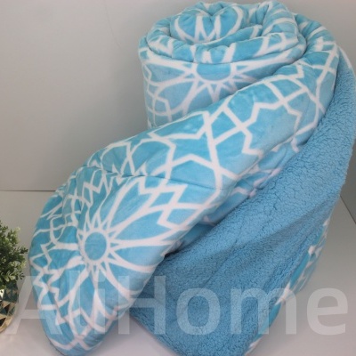 Manta azul claro e branca com padrão geométrico enrolada