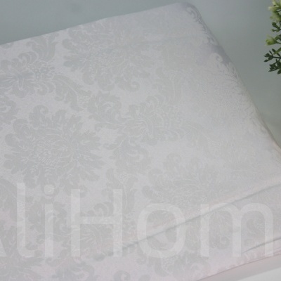 Toalha de mesa branca com padrão floral e vaso dourado decorativo