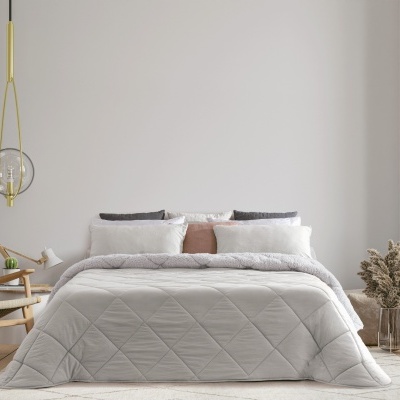 Quarto com cama de casal, edredão cinza claro, almofadas brancas e cor-de-rosa, cadeira de madeira e plantas