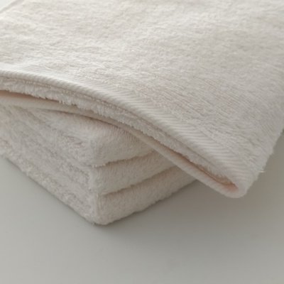 Toalha branca felpuda dobrada sobre superfície clara