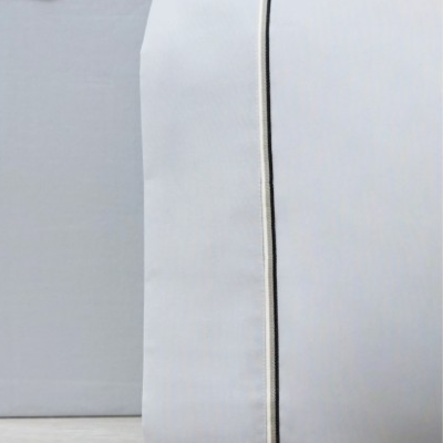 Bolsa de tecido cinzento claro com cordão, sobre superfície de madeira clara