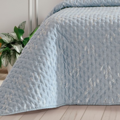 Colcha azul clara com padrão texturizado sobre cama