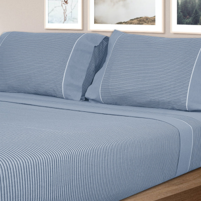 Conjunto de roupa de cama azul às riscas em cama de madeira clara com quadros na parede