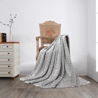 Manta cinza texturizada sobre cadeira antiga junto a cómoda branca em ambiente minimalista