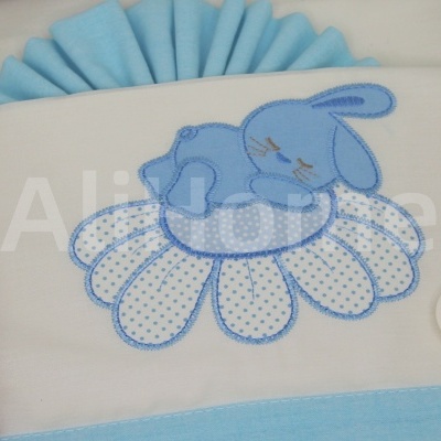 Travesseiro infantil branco com bordado azul de coelho sobre flor azul