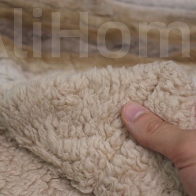 Tecido de pelúcia bege claro sendo segurado por uma mão