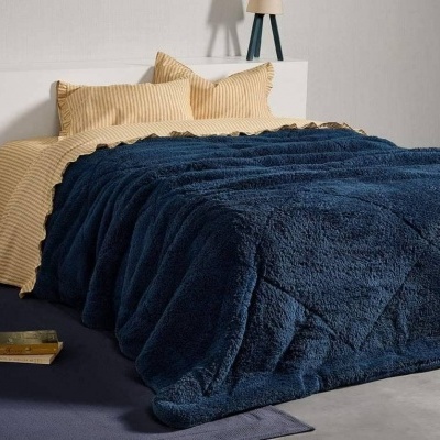 Cama com roupa de cama amarela com riscas e manta azul felpuda em quarto moderno