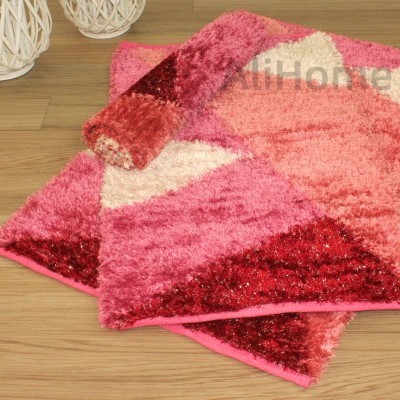 Tapete felpudo colorido com padrão geométrico em tons de rosa e vermelho
