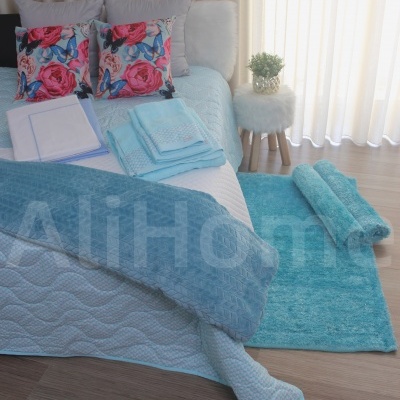 Quarto com cama e conjunto de cama e banho azul e almofadas com padrão floral