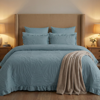 Cama com edredão azul e cabeceira estofada bege em quarto com mesas e candeeiros