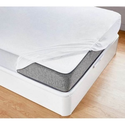 Colchão cinza com lençol branco ajustado numa cama branca sobre chão de madeira clara