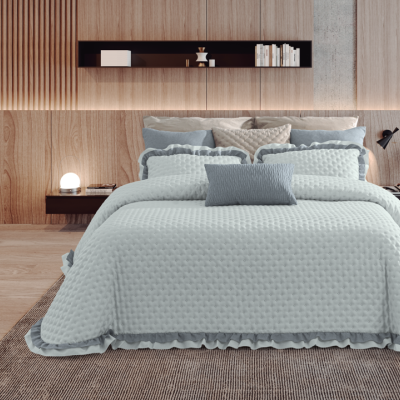 Cama de casal com roupa de cama azul-claro acolchoada e almofadas cinza