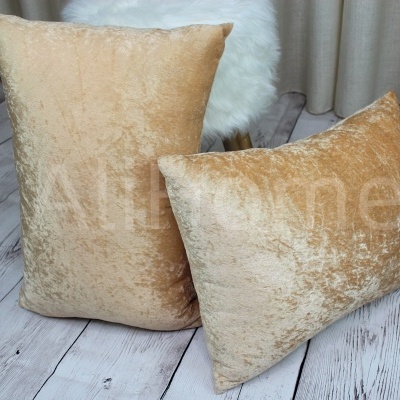 Almofadas bege em tecido aveludado sobre chão de madeira clara