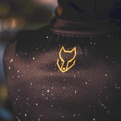 vestuário desportivo preto com padrão de pontos brancos e logótipo amarelo de cabeça de lobo