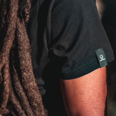 Braço com camisa preta de manga curta e cabelo comprido em dreadlocks