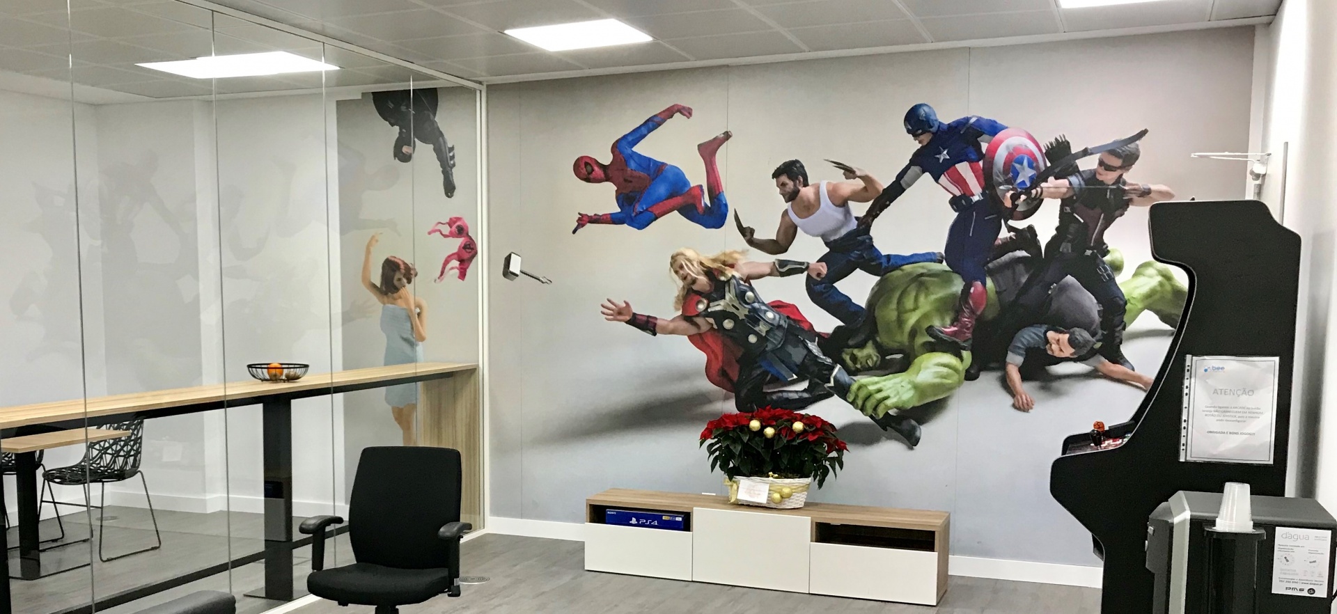 Escritório com parede de vidro e decoração mural dos Vingadores Marvel