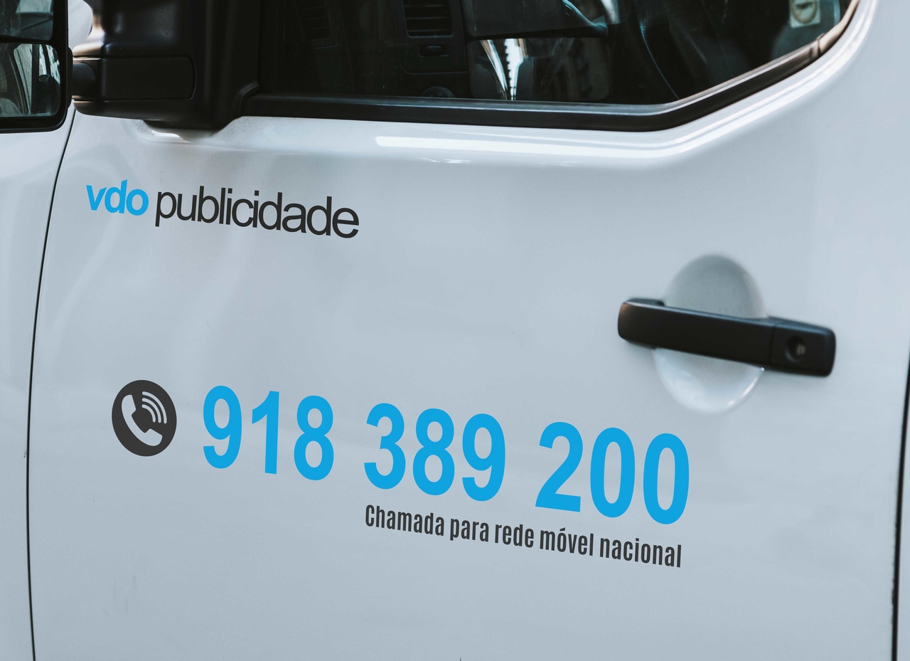 porta de veículo branco com texto publicitário e número de telefone