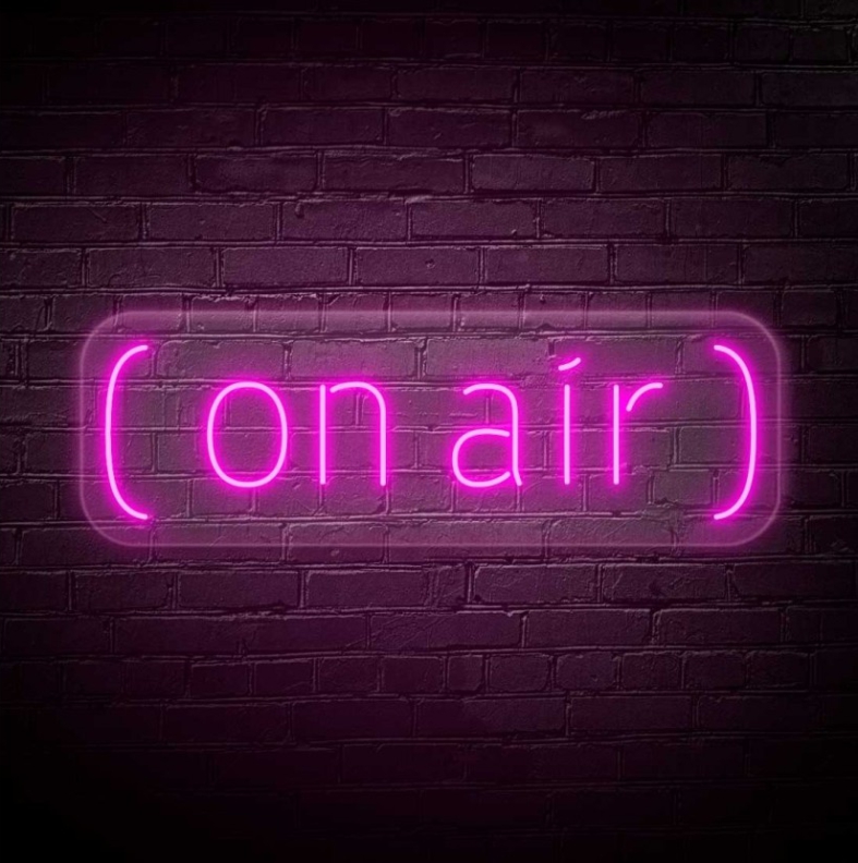 NeonLED | On Air Sinal em néon rosa '(on air)' numa parede de tijolos escuros