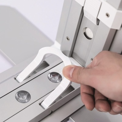 Mão a segurar ferramenta plástica branca sobre estrutura metálica cinzenta