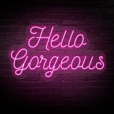 Placa de luz neon rosa com texto Hello Gorgeous numa parede de tijolos escuros
