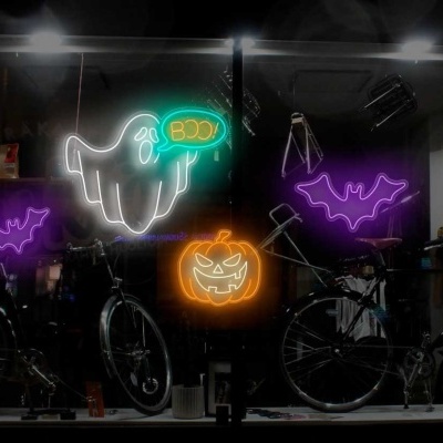 Decorações de néon Halloween com fantasma, abóbora e morcegos em vitrine com bicicletas