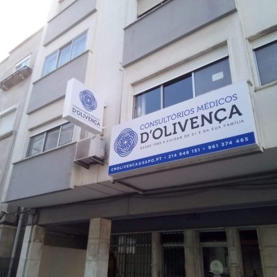 Fachada de consultórios médicos D'Olivença com placas brancas e texto azul