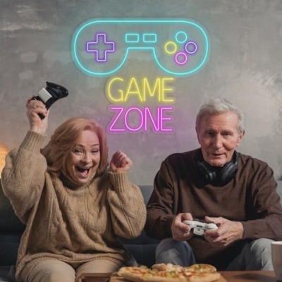 Casal sénior a jogar numa sala com letreiro de néon 'GAME ZONE' na parede atrás.