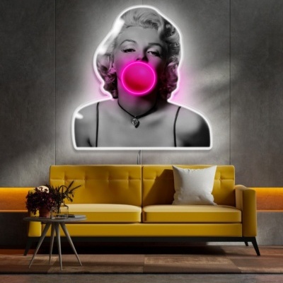 Sofá amarelo com arte mural neon de mulher a estourar chiclete rosa na parede cinza