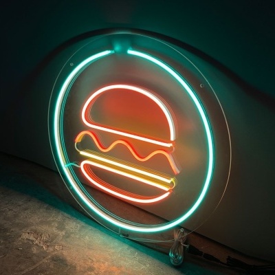 Letreiro de néon redondo com ilustração de hambúrguer encostado a parede escura