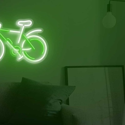 Neon verde em forma de bicicleta na parede de uma sala com sofá cinza e quadro