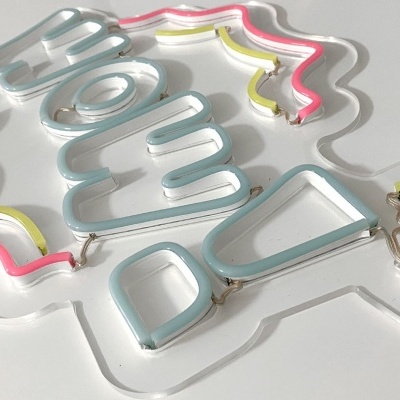 Letreiro de néon com a palavra FLOW em azul claro com linhas amarelas e rosas sobre suporte translúcido