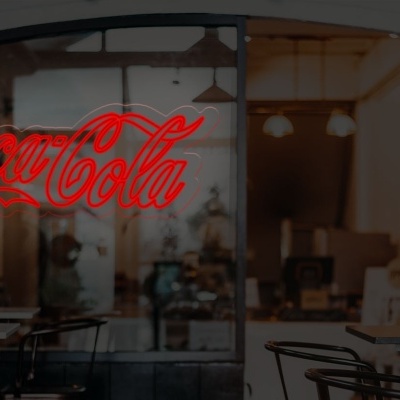 Letreiro luminoso vermelho CocaCola em janela de vidro no interior de café