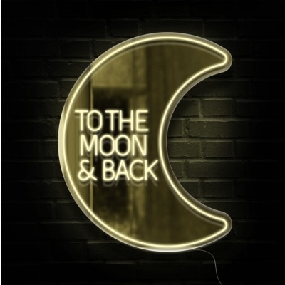 Letreiro de néon em forma de lua com texto TO THE MOON & BACK em parede de tijolos
