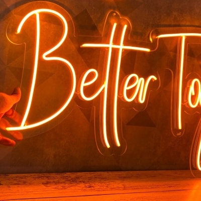 Letreiro luminoso 'Better Together' em néon laranja numa parede cinzenta