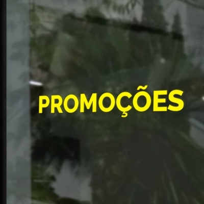 Palavra PROMOÇÕES em letras amarelas num vidro com reflexos