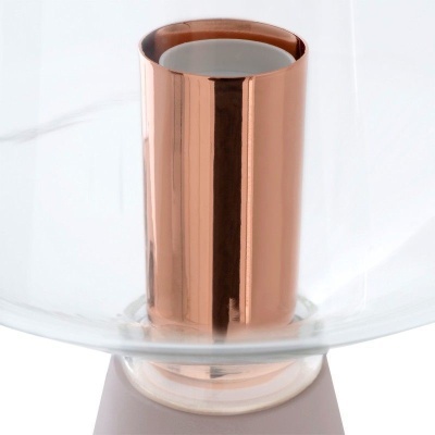 Detalhe de peça metálica de cor cobre e componente transparente sobre base branca